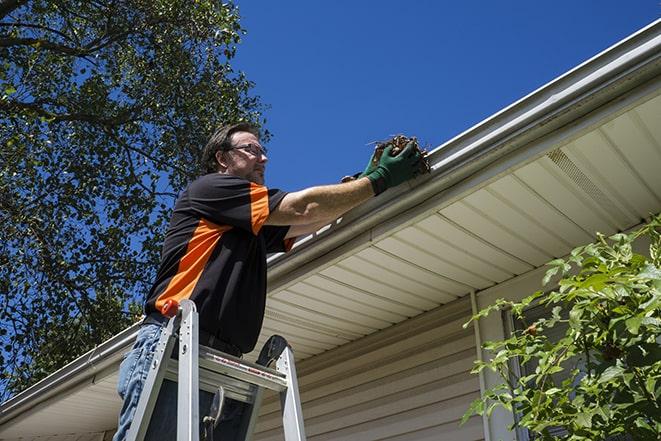 a roofer repairing a damaged gutter on a house in Allen Park